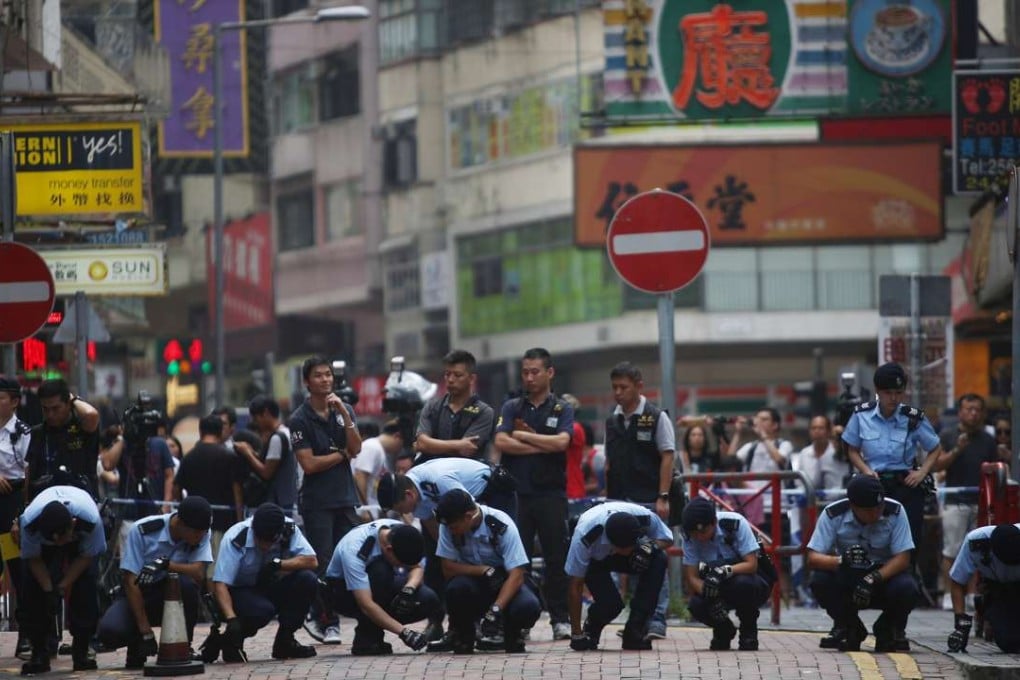 Police scour Parkes Street in Yau Ma Tei for clues. Officers fired four shots just as the bustling neighbourhood was waking up early yesterday. Photo: Sam Tsang