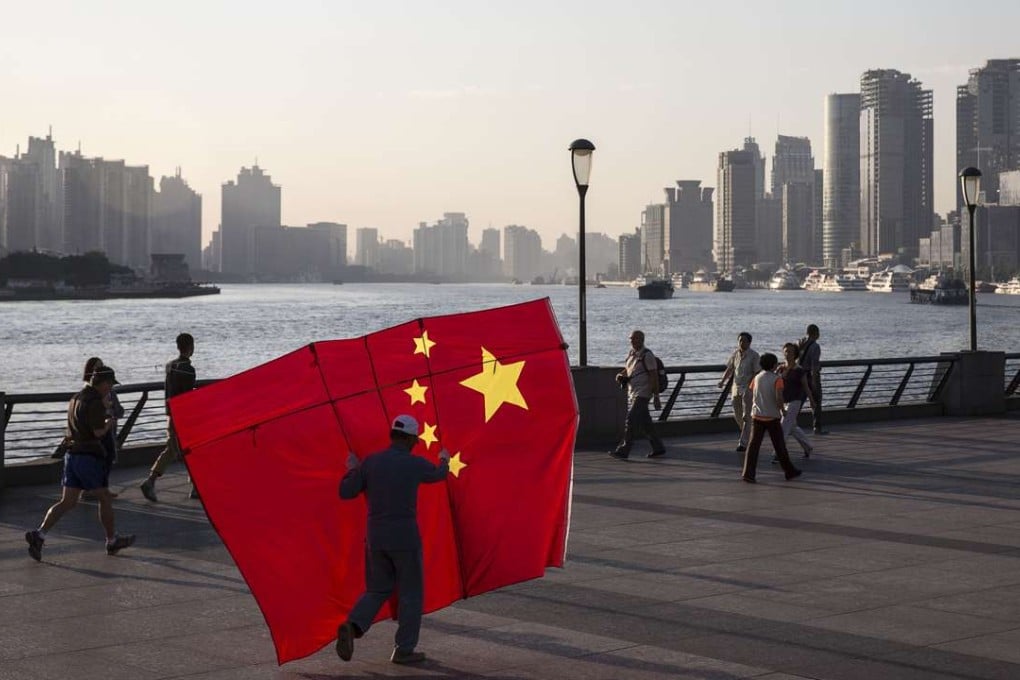 A man carrying a kite in the shape of the Chinese national flag walks along the Bund in Shanghai. Photo: Bloomberg