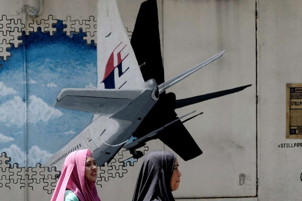 Women walk in front of a mural of missing Flight MH370 in Shah Alam, Malaysia. Photo: AFP
