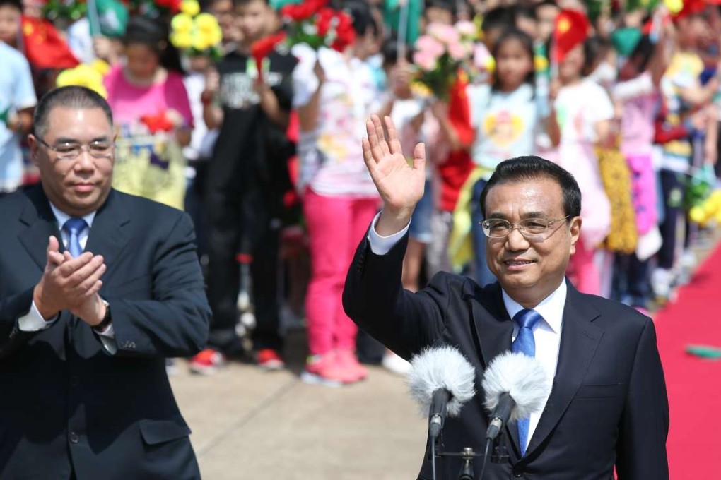 Premier Li Keqiang greets the colourful crowds gathered to welcome him at Macau International Airport on October 10, as Macau Chief Executive Fernando Chui applauds. Photo: Dickson Lee