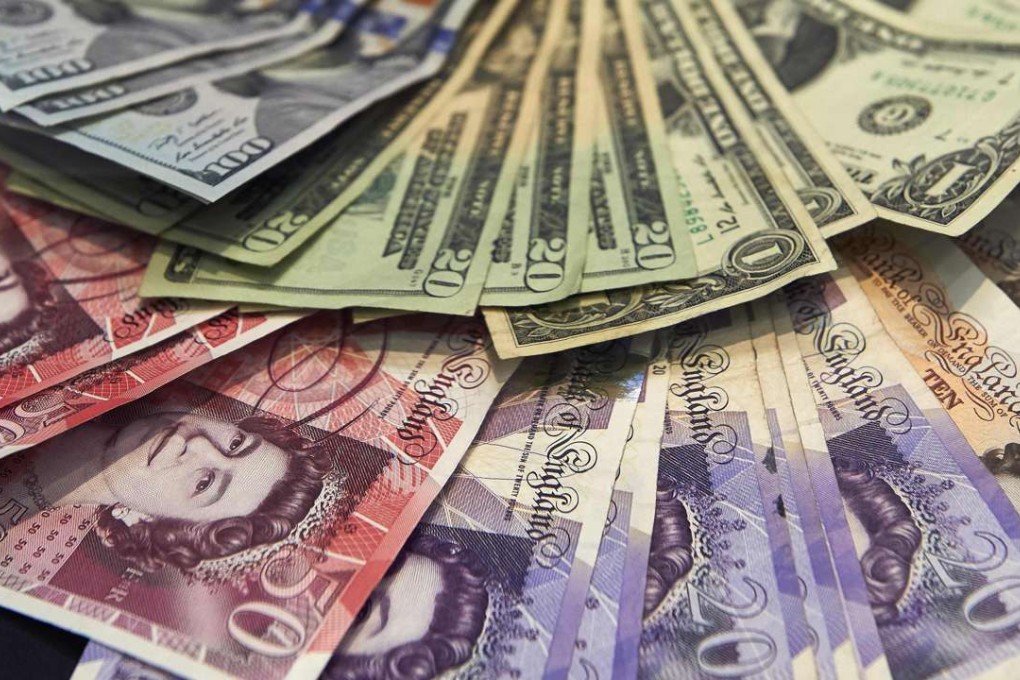 A cashier displaying multiple denomination US dollar and British pound Sterling bank notes for a currency exchange store in central London. Photo: AFP