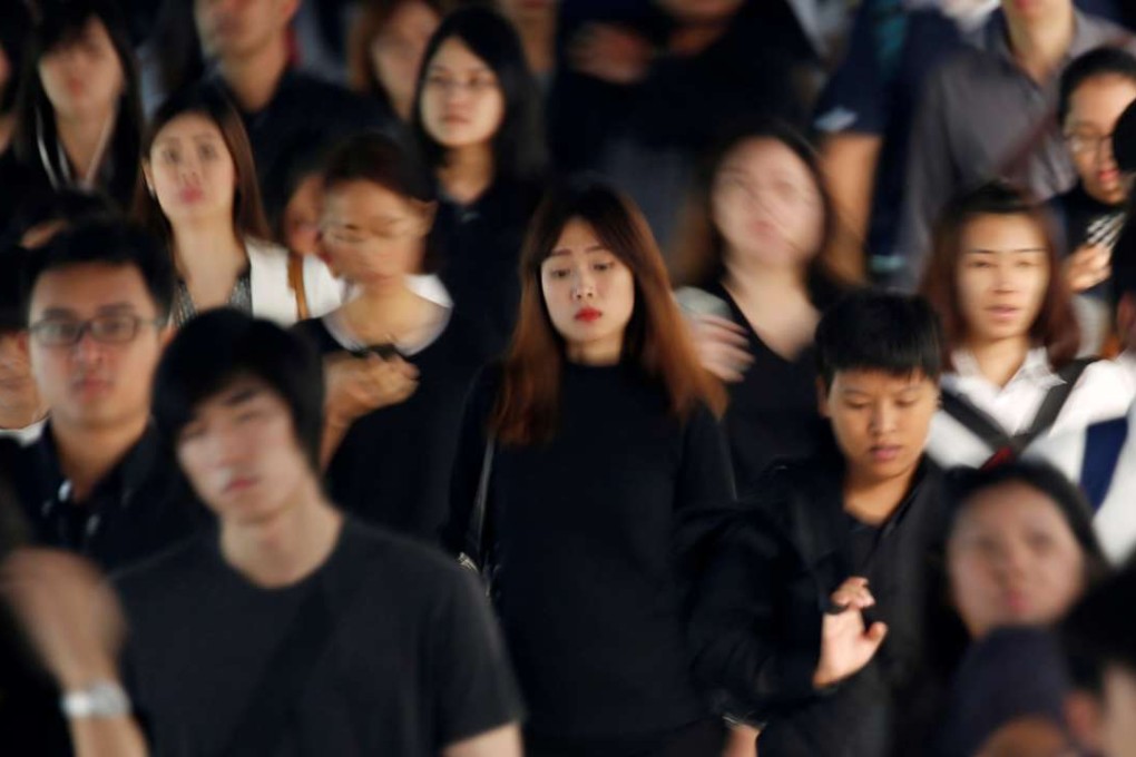 Commuters dressed in black and white or dark coloured clothes, to mourn the passing of Thailand's King Bhumibol Adulyadej, head to work during morning rush hour in Bangkok Monday. Photo: Reuters