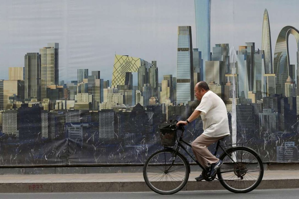 A cyclist passes a poster depicting a future skyline at a construction site in Beijing. Photo: EPA