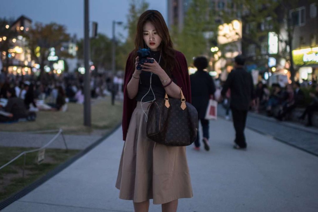 A woman in downtown Seoul uses her mobile phone. We live in an age of public information sharing, and do not need to suffer in silence private acts of shaming. Photo: AFP