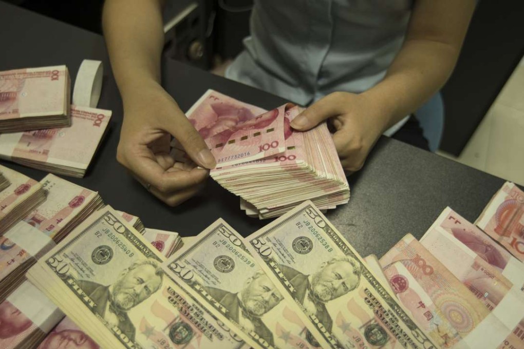 A Chinese clerk counts US dollar and yuan banknotes at a bank in Nantong city, Jiangsu province, China. Photo: AFP