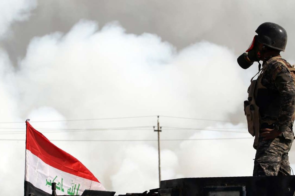 Iraqi forces wear gas masks for protection as smoke billows in the background after Islamic State jihadists torched Mishraq sulphur factory. Photo: AFP