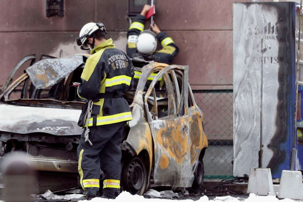 Firefighters investigate a burnt car at the site of an explosion in Utsunomiya, Japan. Photo: Kyodo