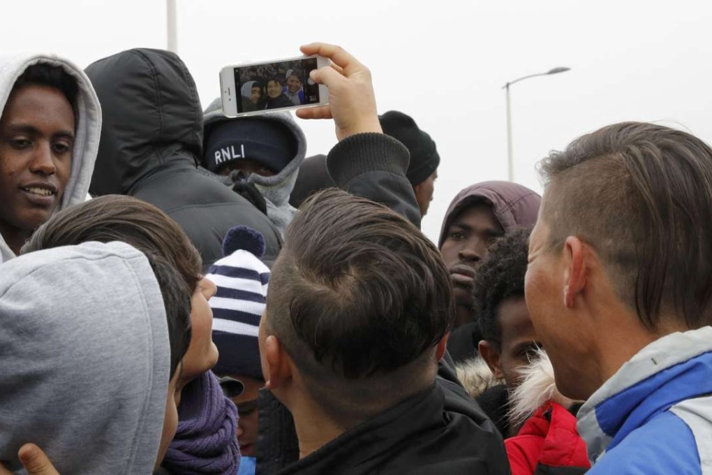 A migrants take a selfie in the queue of an evacuation centre in Calais, France. Photo: Reuters