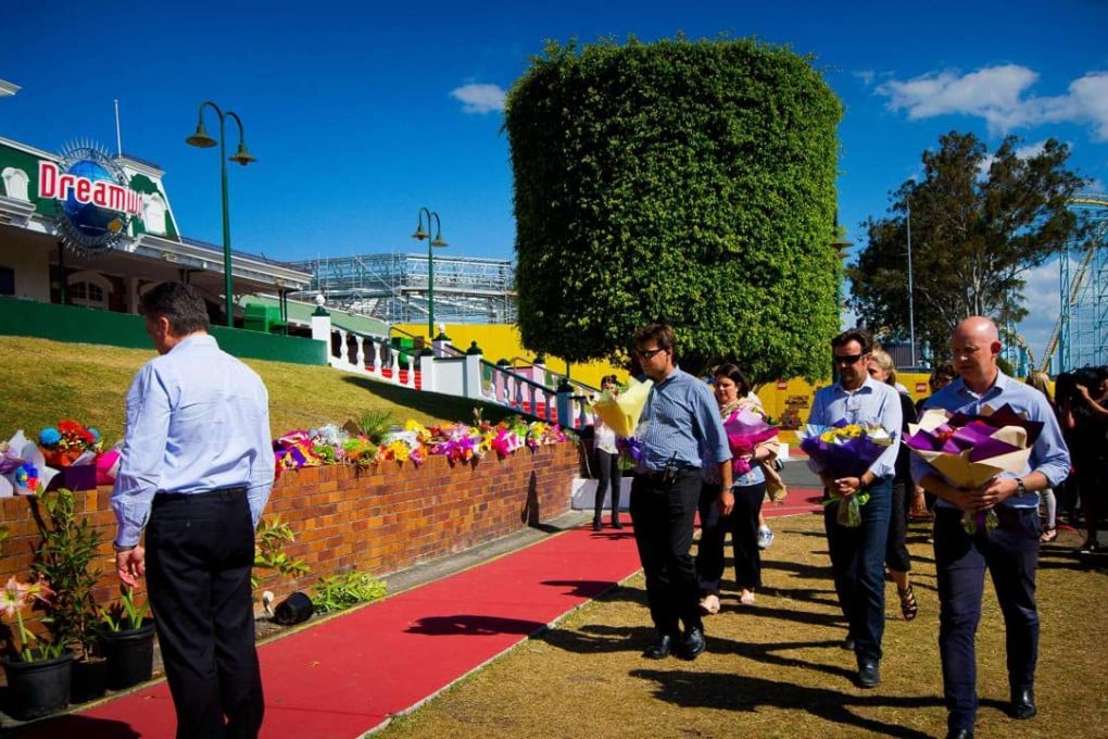 Dreamworld CEO Craig Davidson (left) and staff members lay flowers at a makeshift floral tribute at the Dreamworld theme park on the Gold Coast. Photo: AFP