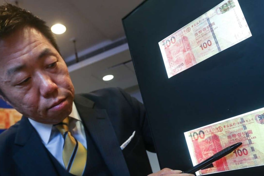 Tommy Cheng Ka-wai, chief inspector of Police, points to a fake HK$100 banknote, with a real one above it for comparison. Photo: K. Y. Cheng