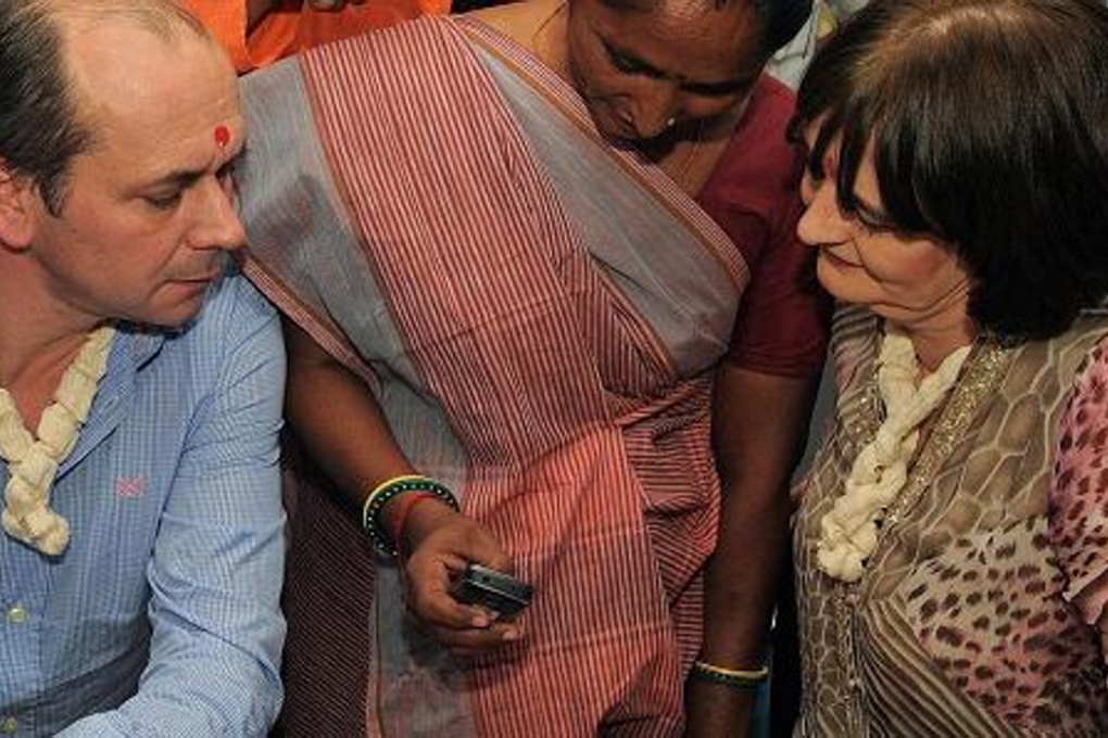 Cherie Blair (R), wife of former British prime minister Tony Blair and chairperson of the Cherie Blair Foundation for Women, and Vodafone Foundation's global director Andrew Dunnett are briefed on a mobile application during their visit to an agricultural processing centre in India. Photo: Sam Panthaky/AFP