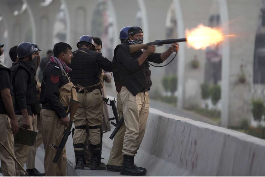 A Pakistani police officer fires a tear gas shell to disperse a crowd protesting against the government in Rawalpindi. Photo: AP