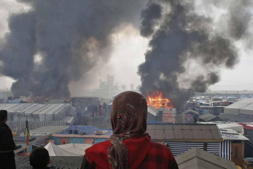 People stand on a hill watching part of the ‘Jungle’ burn. Photo: AP
