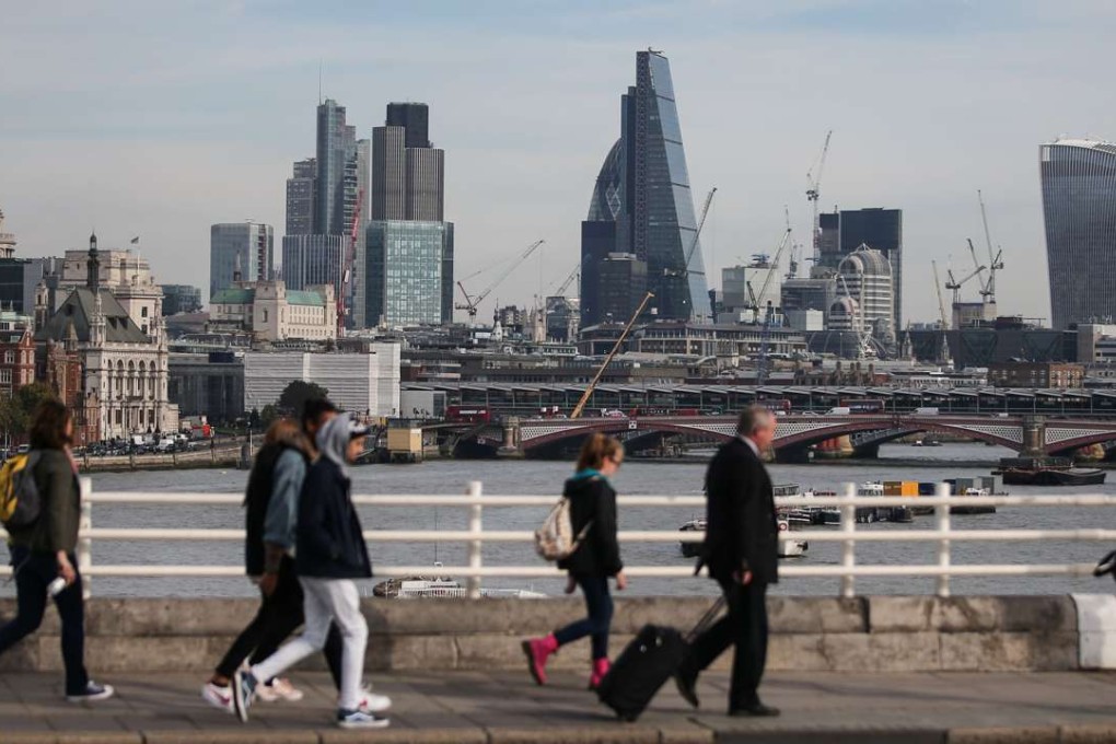 Pedestrians waling through Waterloo Bridge with the skyline of the City of London in the background. Photo: AFP