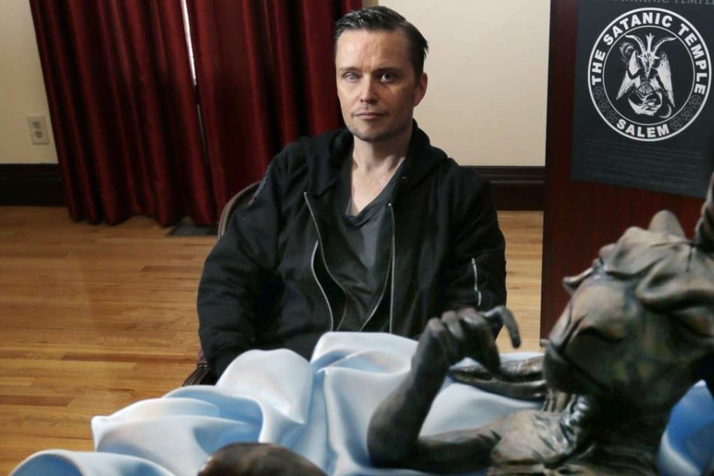 Lucien Greaves sits near a statue of a baby Baphomet inside the recently opened international headquarters of the Satanic Temple in Salem. Photo: AP