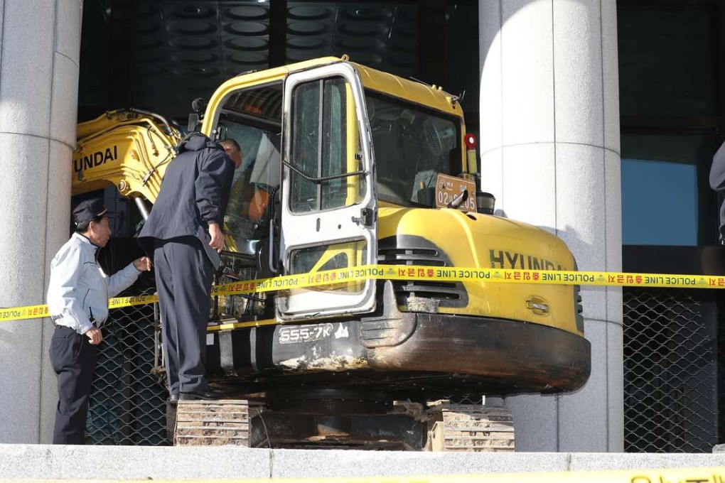 Police officers examine an excavator that was rammed into the entrance of the Supreme Prosecutors' Office in Seoul, South Korea. Photo: EPA