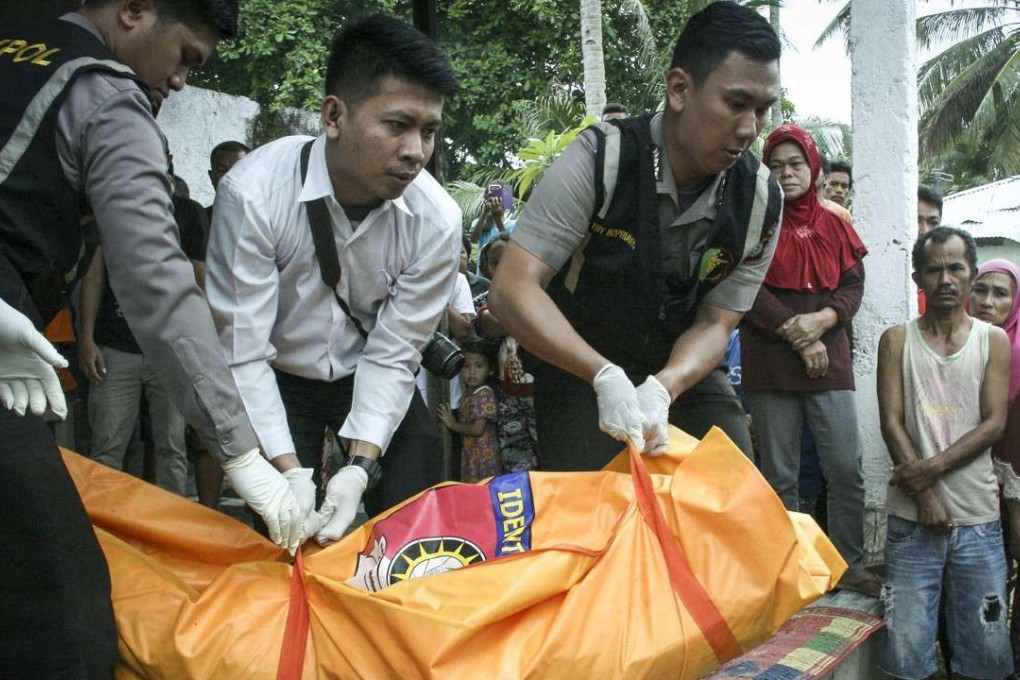 Indonesian forensic police officers carry a body of a victim of a sinking boat for identification. Photo: EPA