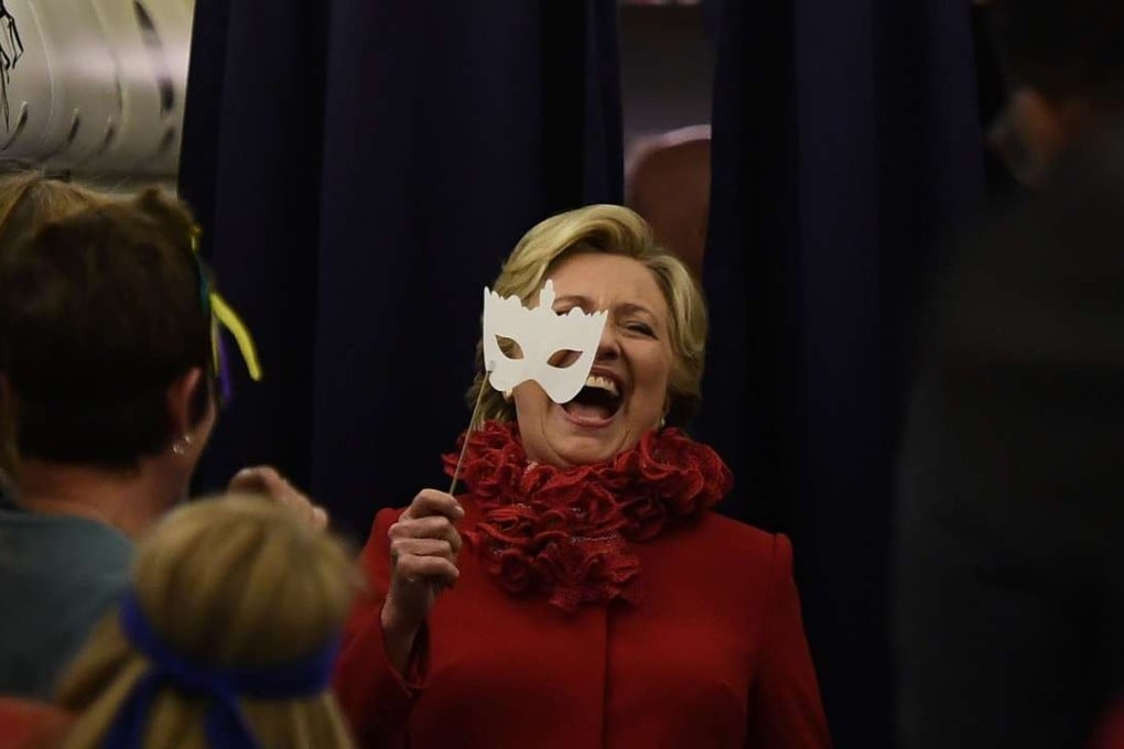 US Democratic presidential nominee Hillary Clinton laughs on Monday night, Halloween, as she holds a mask aboard her campaign plane. Photo: AFP