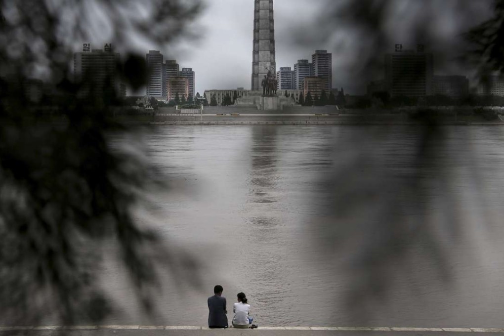 A North Korean couple sit by the river in Pyongyang. Adam Johnson wanted to know about the people who didn’t defect, who strolled beside the river in Pyongyang and had picnics. Picture: AP