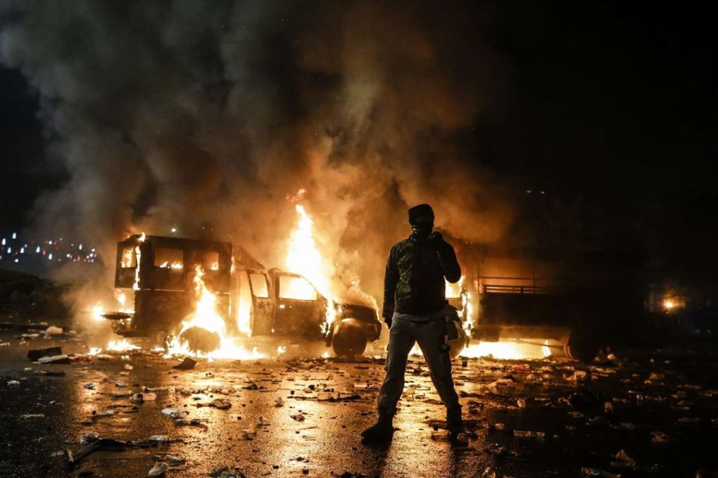 An Indonesian protester walks near burning police cars during a clash with the police at a protest against an allegedly blasphemous remark made by Jakarta's Governor Basuki Tjahaja Purnama. Photo: EPA