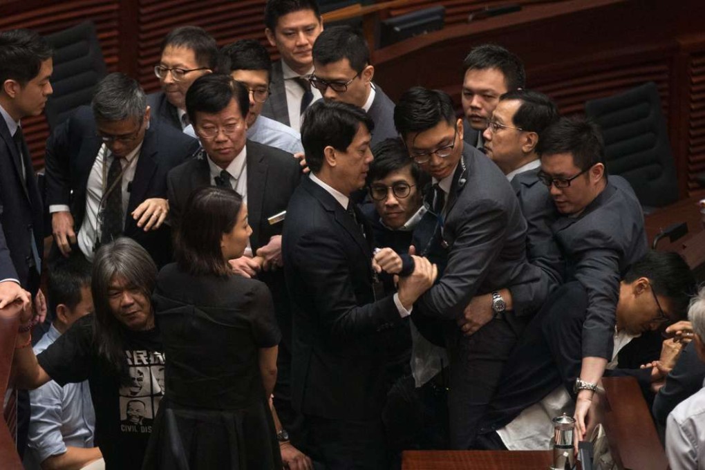 Security guards try to remove legislator-elect Sixtus Leung (centre) from the Legislative Council chamber as pan-democrats create a protective ring around him on November 2. The chaos in the aftermath of the oaths controversy has caused much damage to Hong Kong society. Photo: EPA