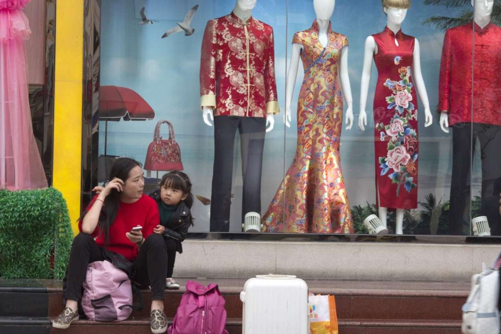 A woman and child rest near a shop window display in Beijing. Photo: AP