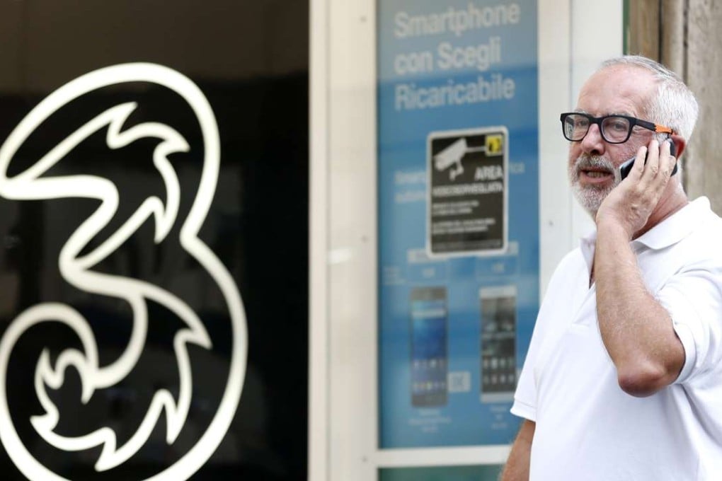 A pedestrian uses his mobile outside a 3 Italia phone store in Rome, operated by CK Hutchison. The Italian unit is merging with VimpelCom’s Wind Telecomunicazioni, in a deal valued at€€21.8 billion. Photo: Bloomberg