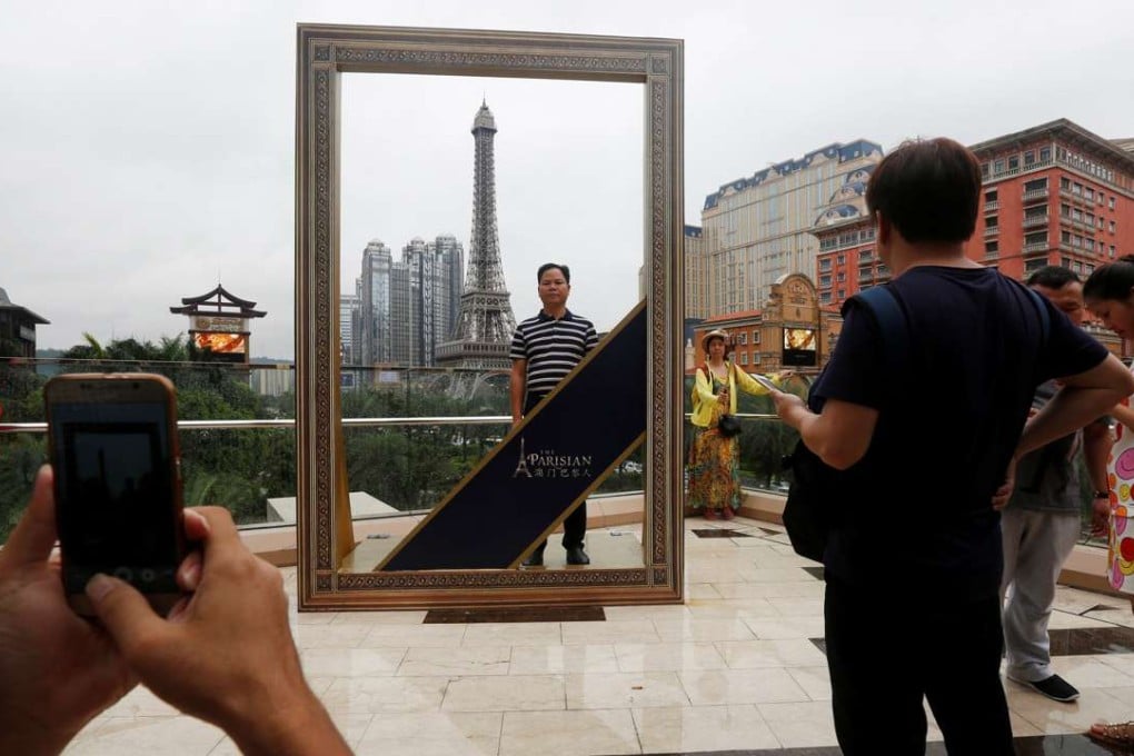 The star of many a thousand picture so far: Visitors take photos in front of the scale replica Eiffel Tower at The Parisian Photo: Reuters