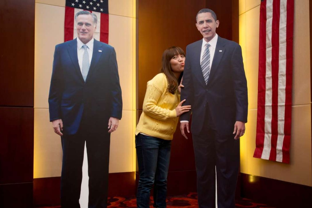 A woman poses with carboard cut-outs of US president Barack Obama (right) and 2012 Republican presidential candidate Mitt Romney at a hotel n Beijing on November 7, 2012. Photo: AFP