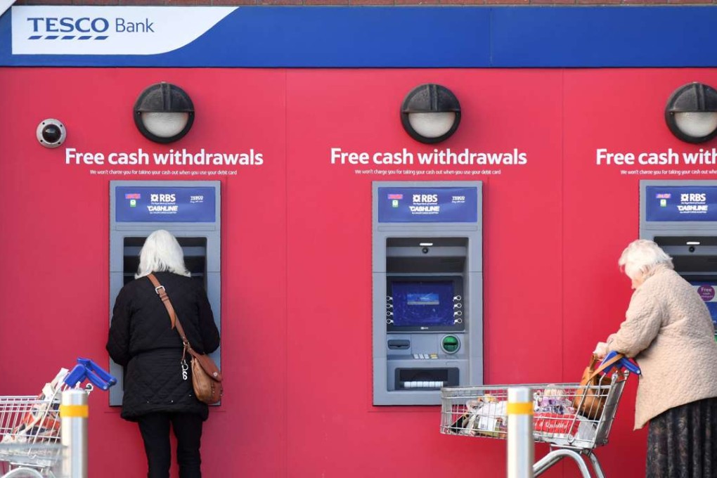 Customers use a Tesco Bank cash point in Liverpool, northwest England, on Monday. Photo: AFP