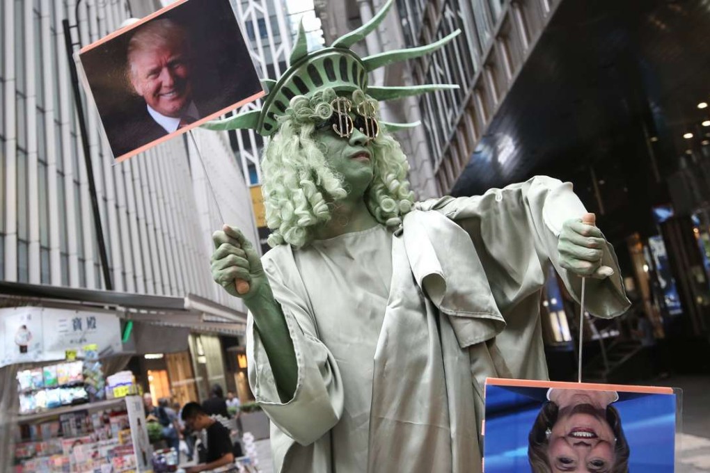 Andrew So, director of HK Funny Clown Theatre, dressed as the Statue of Liberty, holds photos of Donald Trump and Hillary Clinton in downtown Hong Kong on Wednesday. Many observers expect some major changes to US foreign policy ­towards Asia during Trump’s presidency. Photo: David Wong