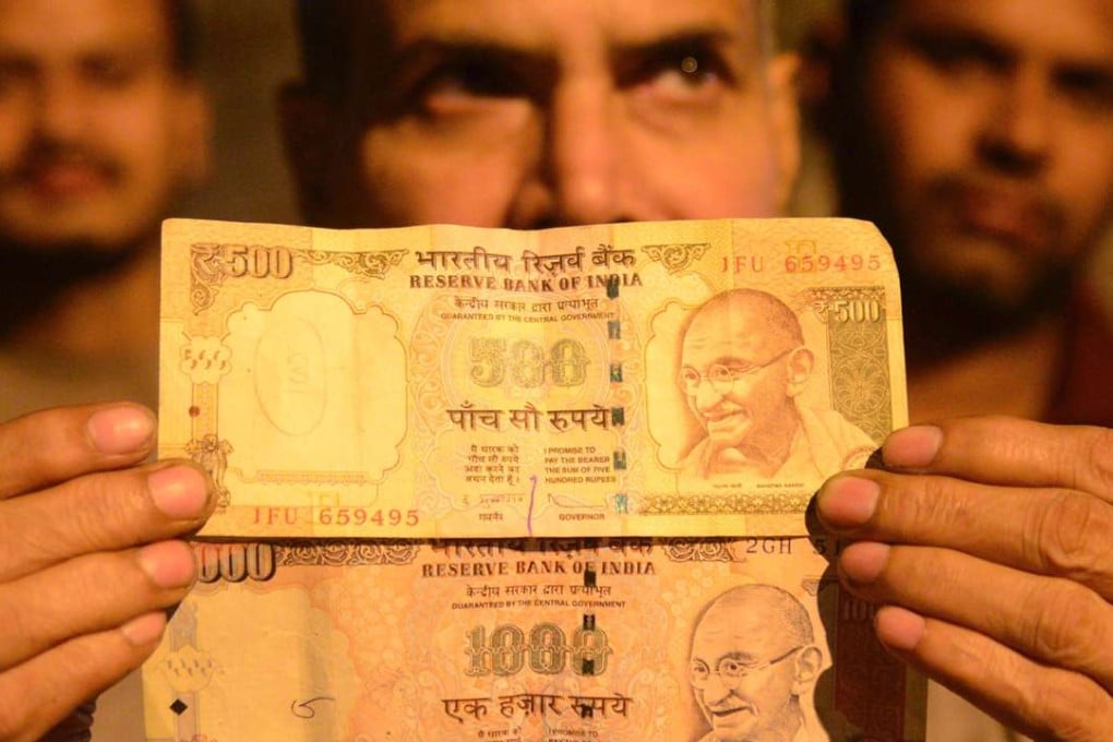 An Indian man holds 500 and 1000 notes. Even with the growth of credit cards, Indians routinely use cash. About 30 per cent of all land transactions involve cash, analysts say, and land is the preferred parking place for politicians, businessmen and movie stars seeking to hide illegal money. Photo: AFP