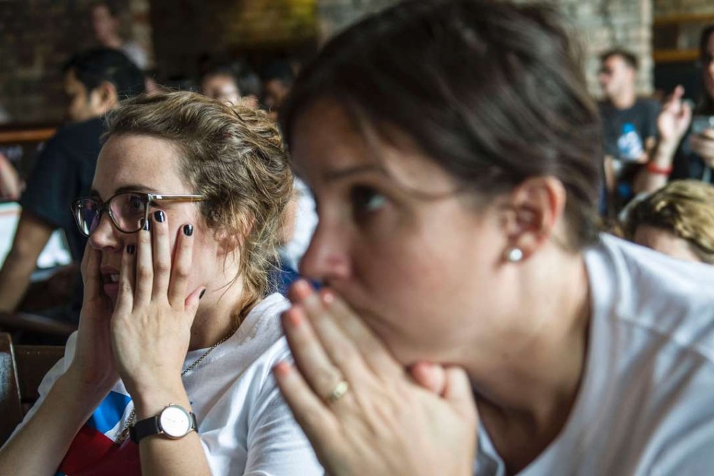 American supporters of Hillary Clinton take in the news of her defeat as they watch a live broadcast of the US presidential election at a restaurant in Yangon on November 9. Photo: AFP