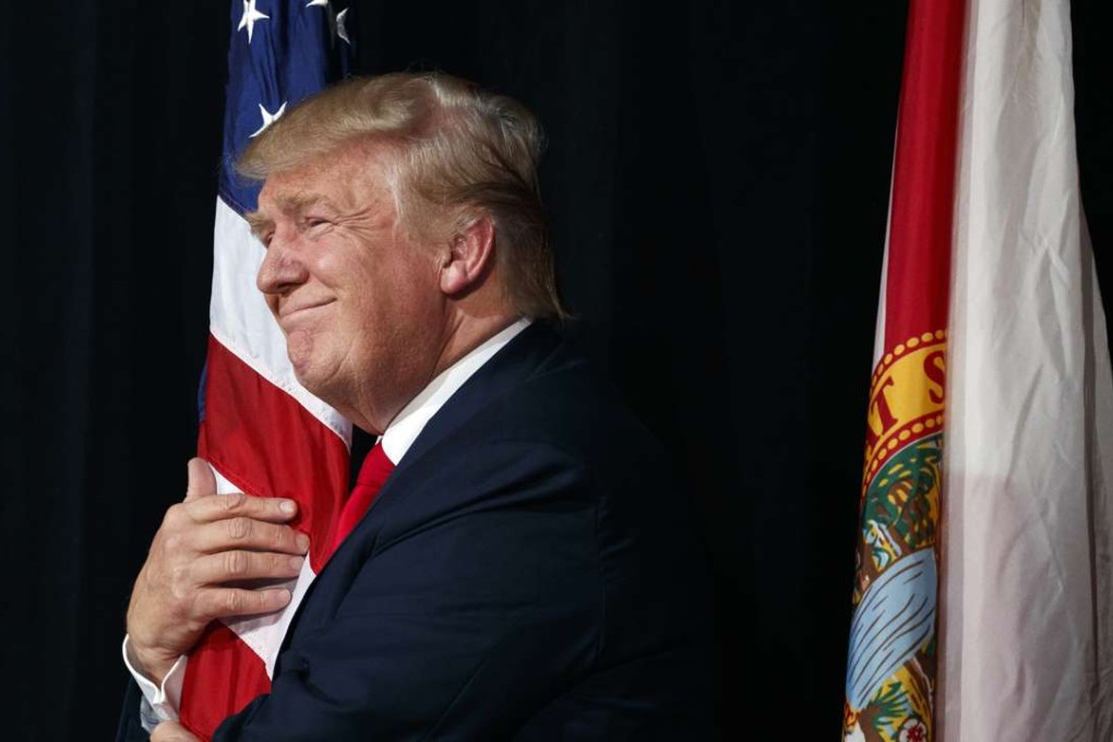 Republican presidential candidate Donald Trump hugs a the American flag as he arrives to speak to a campaign rally last month in Tampa, Florida. Photo: AP