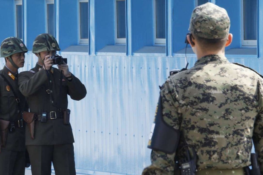 A North Korean soldier takes photographs of the south as a South Korean soldier stands guard at the ‘Truce Village’ of Panmunjom in the demilitarised zone. US President-elect Donald Trump pledged his commitment to defend South Korea under an existing security alliance. File photo: Reuters