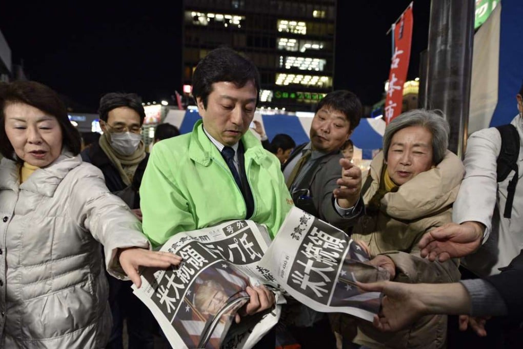 Passers-by in Tokyo reach for extra editions of newspapers reporting Donald Trump’s victory in the US presidential election on November 9. Photo: EPA