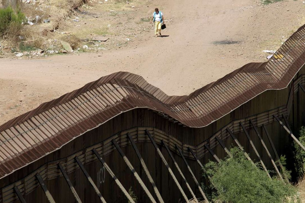 A woman walks along a dirt road on the Mexican side of the border next to the steel wall that separates Mexico from Arizona. Photo: AFP