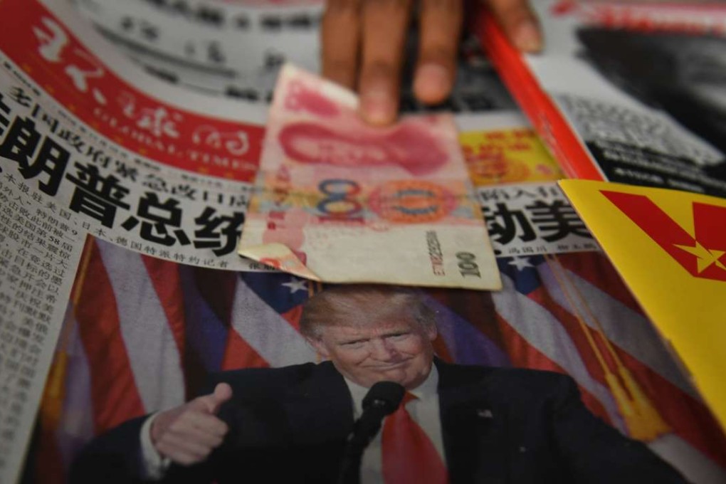 A vendor picks up a 100 yuan note above a newspaper featuring a photo of US president-elect Donald Trump, at a news stand in Beijing. Photo: AFP