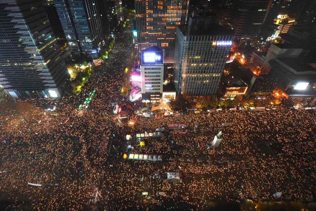 Protesters hold candles during an anti-government rally in central Seoul on November 12, 2016. Pressure on South Korea's scandal-hit president to resign escalated sharply on November 12, with organisers claiming a million-strong turnout at one of the largest -- and loudest -- anti-government protests the country has ever witnessed. / AFP PHOTO / JUNG YEON-JE