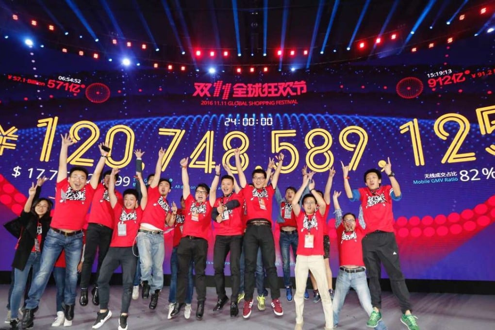 Staff members celebrate in front of a giant screen displaying total gross merchandise volume of Alibaba's Tmall online marketplace for the Singles' Day shopping spree, in Shenzhen, Guangdong Province. Photo: Xinhua