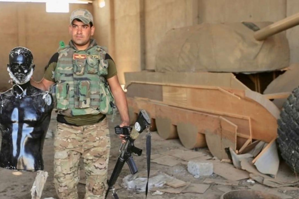 An Iraqi soldier poses with a bearded mannequin and a tank made of wood in Bawiza, north of Mosul, Iraq, on Sunday Photo: Reuters
