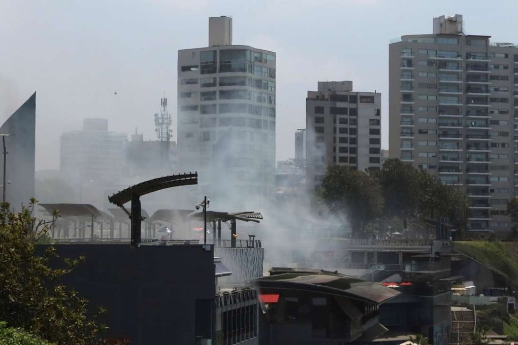 Smokes rises above the seaside Larcomar shopping centre while people struggling to breathe were helped into ambulances. Photo: Reuters