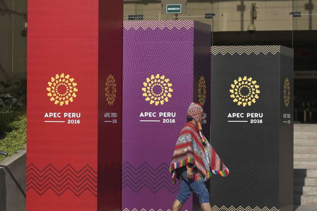 A man dressed in traditional Andean clothes walks past the logo of the APEC 2016 summit in Lima, Peru. Photo: AP