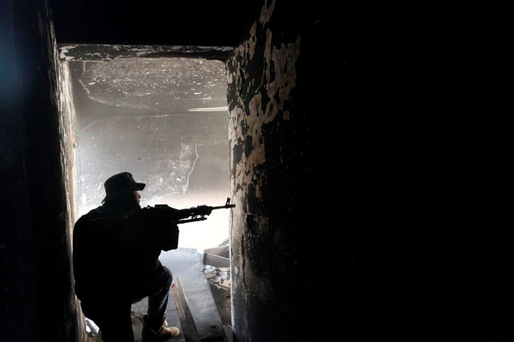 A fighter of Libyan forces aims his weapon as he takes up position inside a ruined house at the front line of fighting with Islamic State militants in Ghiza Bahriya district. Photo: Reuters