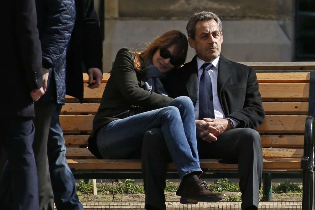 Former French President Nicolas Sarkozy sits on a bench with his wife, singer Carla Bruni-Sarkozy, after voting at a polling station in the first round in the French mayoral elections in Paris, in this March 23, 2014, photo. Photo: Reuters