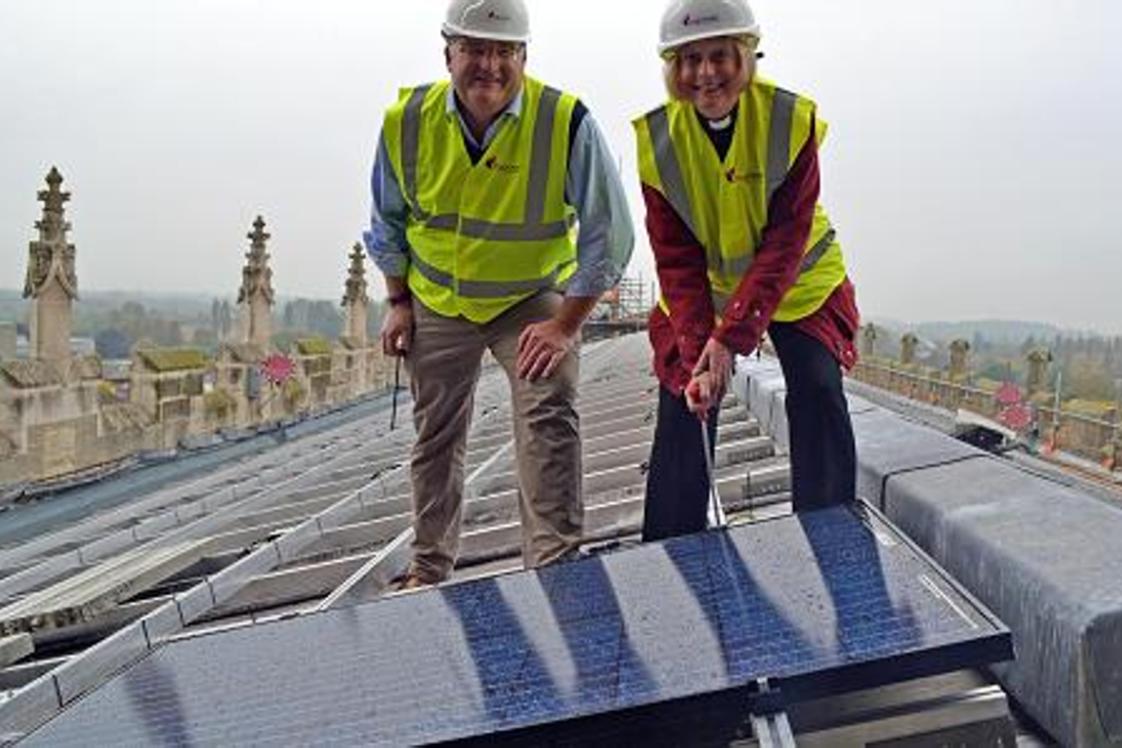 Canon Celia Thomson bolts in the first solar panel on top of Gloucester Cathedral, in south west England. Photo: Mypower