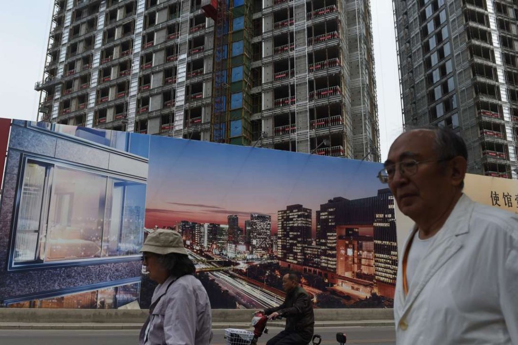 People walk past a billboard advertising a new housing complex outside a construction site in Beijing. Some developers are desperate to acquire land in the nation’s capital. Photo: AFP