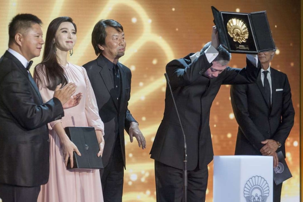 Feng Xiaogang holding aloft his "Concha de Oro" (Golden Shell) award for the film I am not Madame Bovary beside the Silver Shell Best Actress winner Fan Bingbing during the 64th San Sebastian International Film Festival in September. Photo: AFP