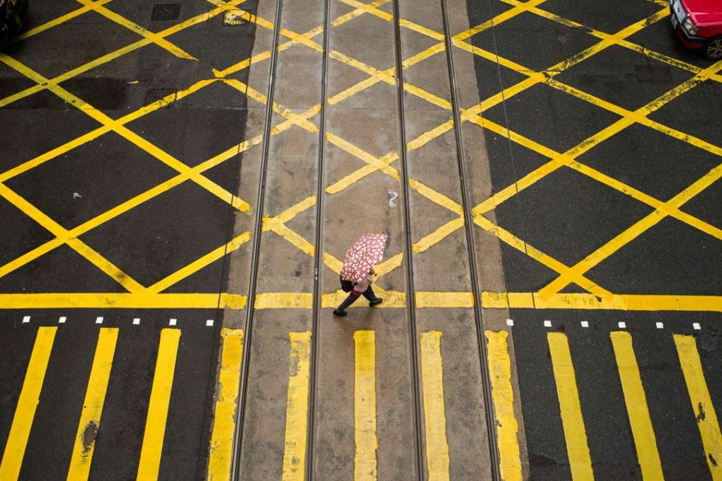 A pedestrian crosses a road in Hong Kong. Hong Kong’s economy is unapologetically capitalist, while the mainland is a socialist state. The assumption that the mainland will eventually become capitalist and converge with our economy is too simplistic. Photo: AFP