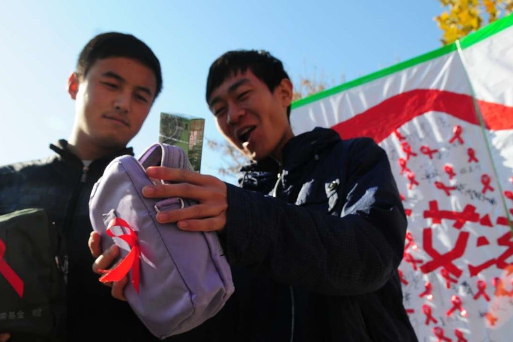 Two Chinese college students show off their World Aids Day Red Ribbon health packs, which include packets of condoms, during a campaign in Liaocheng, Shandong province. Photo: AFP